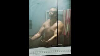 健美运动员在淋浴前在雾蒙蒙的镜子中散装弯曲